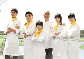 요리사를 꿈꾸는 청소년들이 팔짱을 끼고 포즈를 취하며 셰프와 함께 미소를 짓고 있습니다.