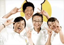 요리사를 꿈꾸는 청소년들이 양손으로 브이표시를 하며 셰프와 함께 환하게 웃고 있습니다.